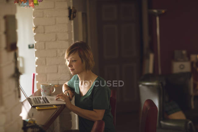 Belle femme utilisant un ordinateur portable à la maison — Photo de stock