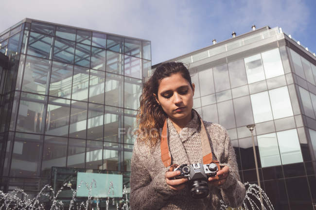 Mujer revisando foto con cámara digital en la ciudad - foto de stock