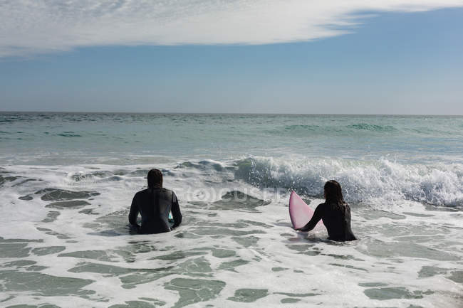 Vue arrière du couple surfeur surfant sur la plage — Photo de stock