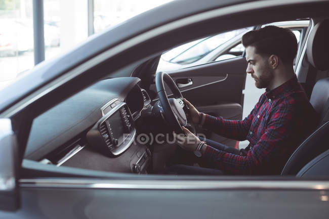 Handsome salesman examining car at showroom — Stock Photo