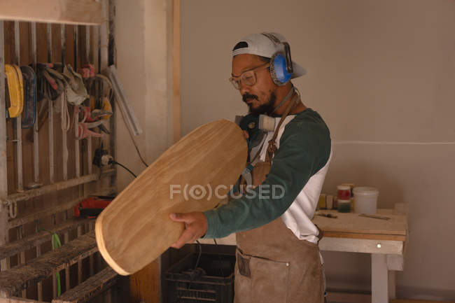 Человек осматривает скейтборд в мастерской — стоковое фото