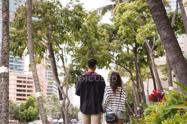 Vista posteriore della coppia che cammina insieme sul marciapiede in città — Foto stock