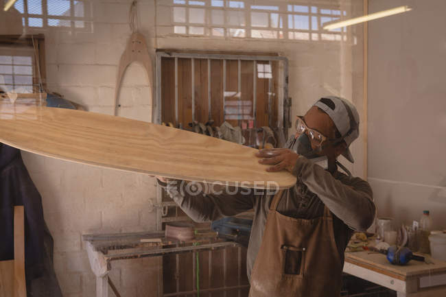 Человек делает скейтборд в мастерской — стоковое фото