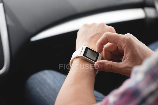 Mid section of man using smartwatch in a car — Stock Photo