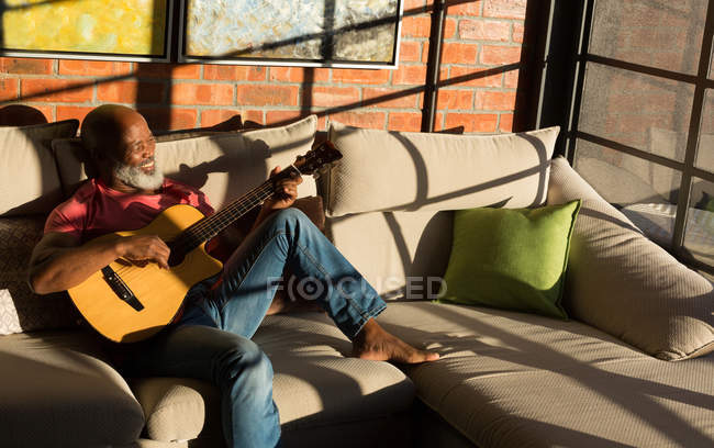 Uomo anziano attivo che suona la chitarra a casa — Foto stock