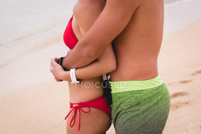 Sección media de la pareja abrazándose en la playa - foto de stock