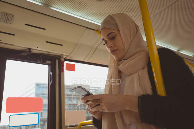 Hermosa mujer hijab utilizando el teléfono móvil en el autobús - foto de stock