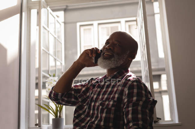 Старший графический дизайнер разговаривает по мобильному телефону в офисе — стоковое фото