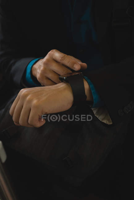 Средняя секция бизнесмена, использующего умные часы в автобусе — стоковое фото