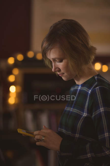 Вид сбоку красивой женщины, пользующейся мобильным телефоном дома — стоковое фото