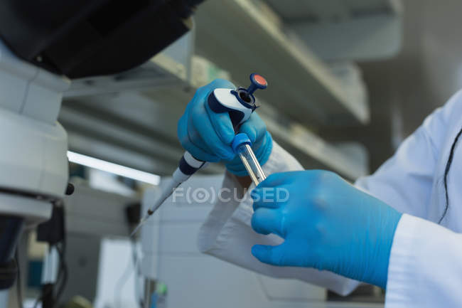 Científico analizando una muestra en un tubo de ensayo en el laboratorio - foto de stock