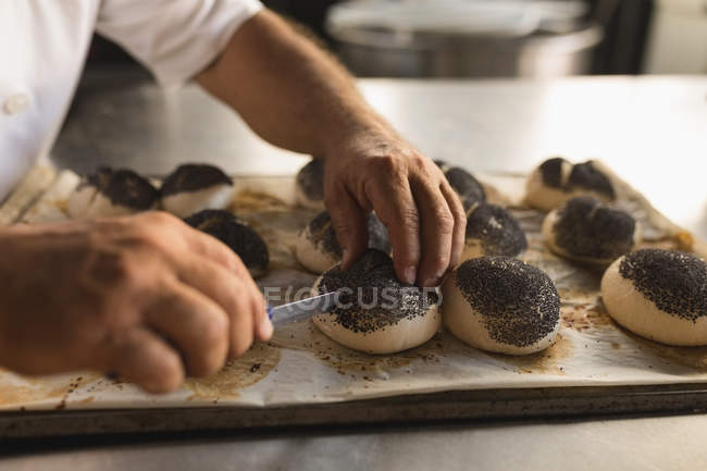 Panadero masculino preparando croissants redondos en panadería - foto de stock