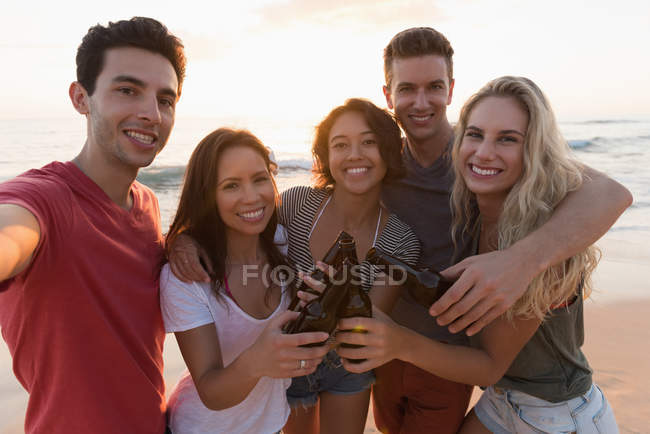 Група щасливих друзів, що стоять разом на пляжі — стокове фото