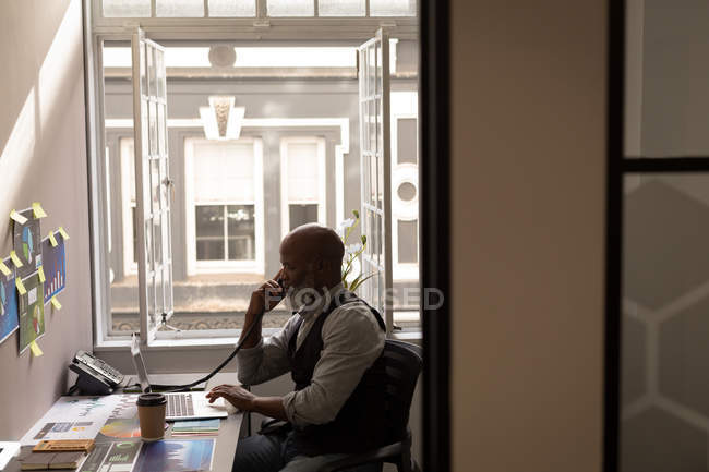 Designer gráfico sênior falando no telefone fixo na mesa no escritório — Fotografia de Stock