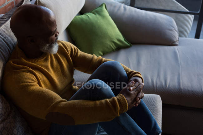 Pensativo hombre mayor relajarse en el sofá en casa - foto de stock