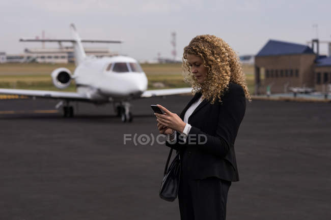Beautiful businesswoman using mobile phone at terminal — Stock Photo