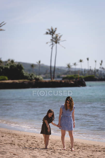 Mère et fille marchent ensemble sur la plage par une journée ensoleillée — Photo de stock
