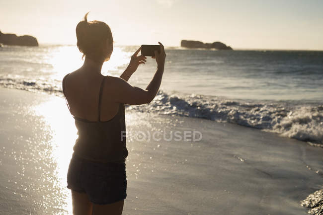 Женщина-волейболистка фотографируется с мобильного телефона на пляже — стоковое фото