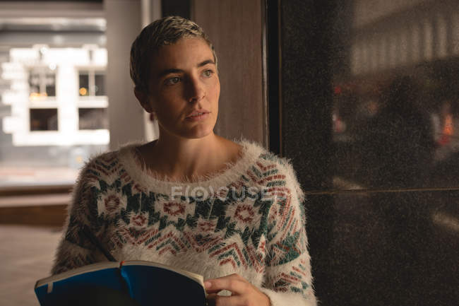 Nachdenkliche Geschäftsfrau schreibt in der Cafeteria im Büro an einem Buch — Stockfoto
