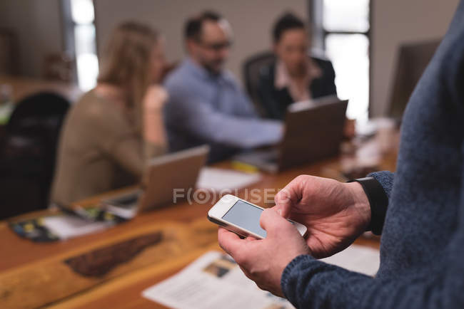 Середина чоловічої виконавчої влади з використанням мобільного телефону в офісі — стокове фото