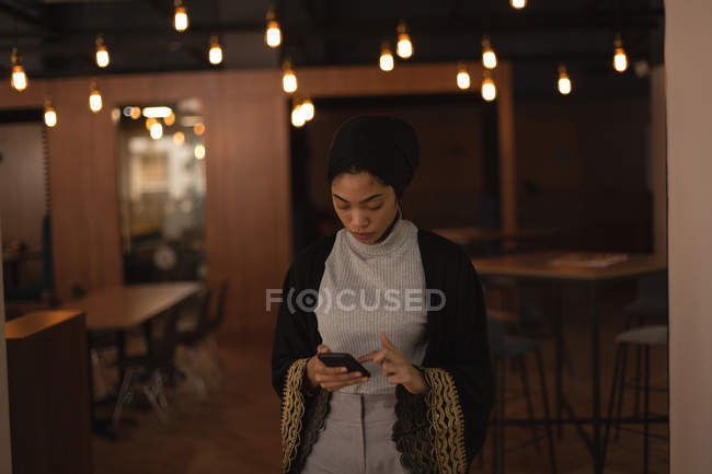 Businesswoman in hijab using mobile phone at office cafeteria — Stock Photo