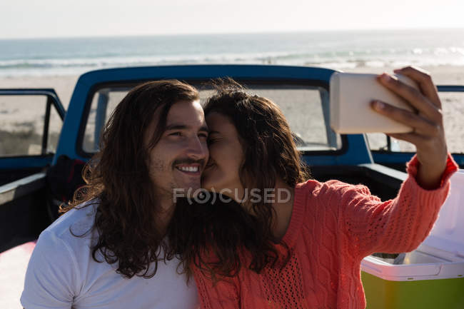 Couple taking selfie with mobile phone in a pickup truck at beach — Stock Photo