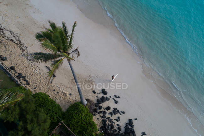 Aerea di donna con tavola da surf a piedi sulla spiaggia — Foto stock