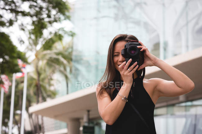 Femme cliquetant photo avec appareil photo numérique dans la ville — Photo de stock