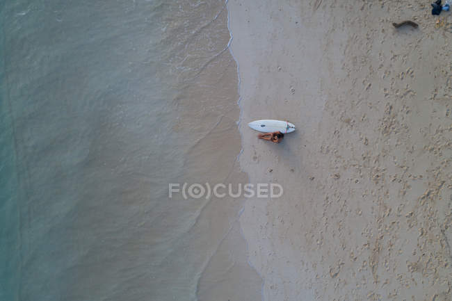 Aerial of woman with surfboard sitting on the beach — Stock Photo