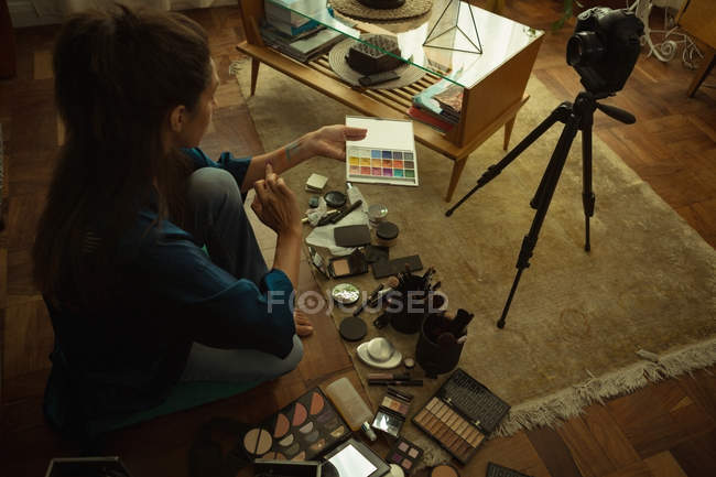Mujer video blogger grabación de vídeo vlog con accesorios de maquillaje en casa - foto de stock