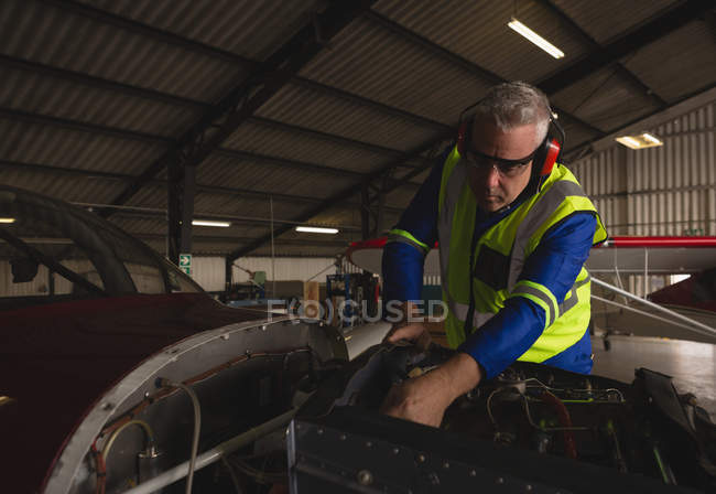 Ingenieur überprüft Flugzeugtriebwerk im Hangar — Stockfoto