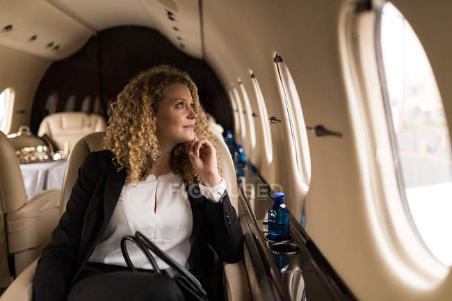 Задумчивая деловая женщина, путешествующая на частном самолете — стоковое фото