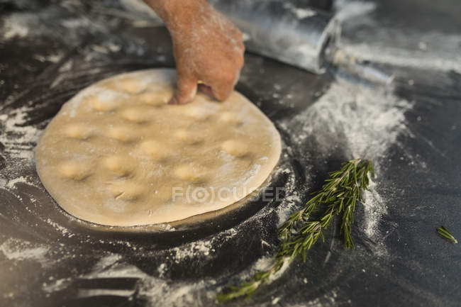 El panadero masculino amasando la masa en la pastelería - foto de stock
