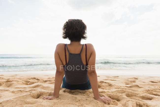 Rückansicht einer Frau, die sich am Strand entspannt — Stockfoto