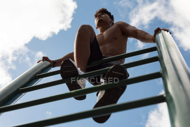 Junger Mann turnt im Park am Reck — Stockfoto