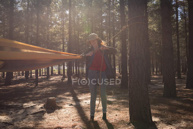 Frau bindet Hängemattengurt an Baum im Wald — Stockfoto