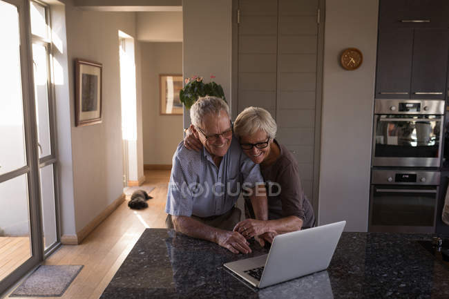 Senior couple video calling on laptop in kitchen at home — Stock Photo
