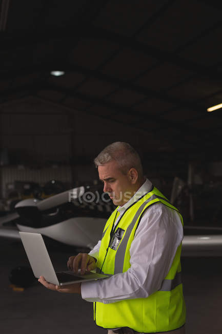 Membro da tripulação usando laptop no hangar aeroespacial — Fotografia de Stock