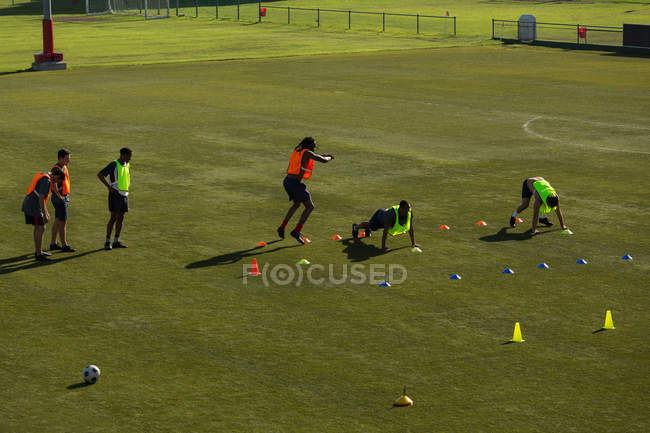 Jugadores haciendo ejercicio en el campo de deportes en un día soleado - foto de stock