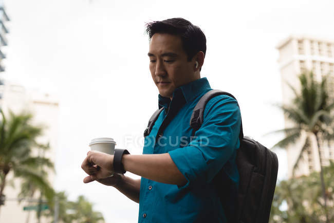 Homem inteligente verificando o tempo em smartwatch na rua da cidade — Fotografia de Stock