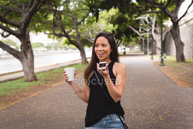 Mulher falando no celular andando na calçada da cidade — Fotografia de Stock