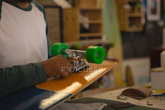 Metà sezione di uomo che fa skateboard in officina — Foto stock