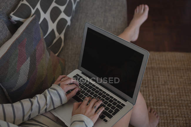 Low section of woman using laptop at home — Stock Photo