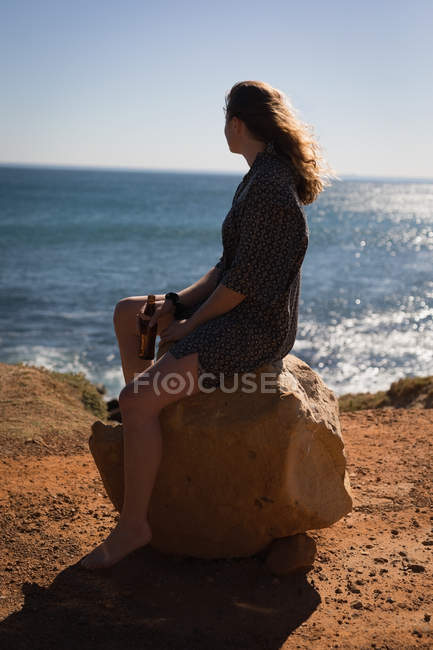 Nachdenkliche Frau sitzt auf einem Felsen am Strand — Stockfoto
