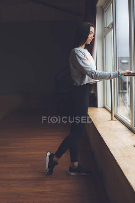 Thoughtful female dancer looking through window in dance studio — Stock Photo