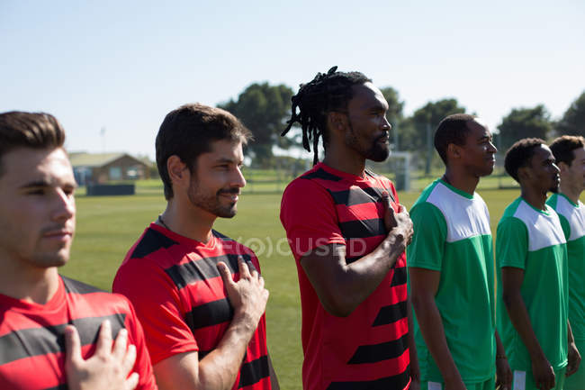 Jugadores rindiendo homenaje al país antes del partido en tierra - foto de stock