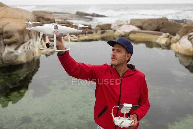 Hombre operando un dron volador en el campo - foto de stock
