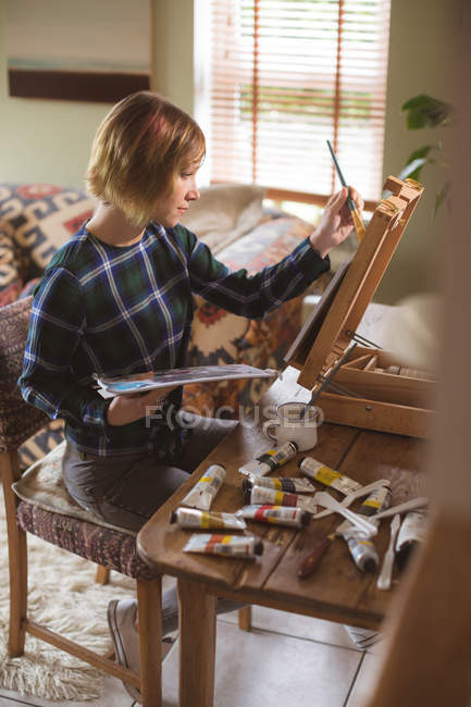 Artista feminina pintura imagem sobre tela na sala de estar em casa — Fotografia de Stock