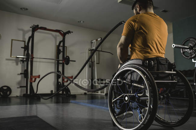 Инвалид на инвалидной коляске тренируется с боевыми веревками в тренажерном зале — стоковое фото