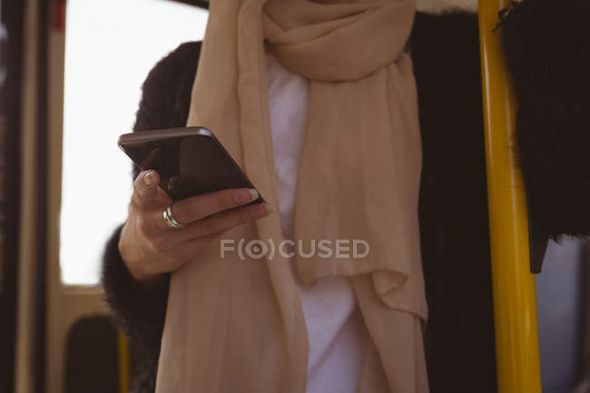Seção intermediária da mulher hijab usando telefone celular no ônibus — Fotografia de Stock